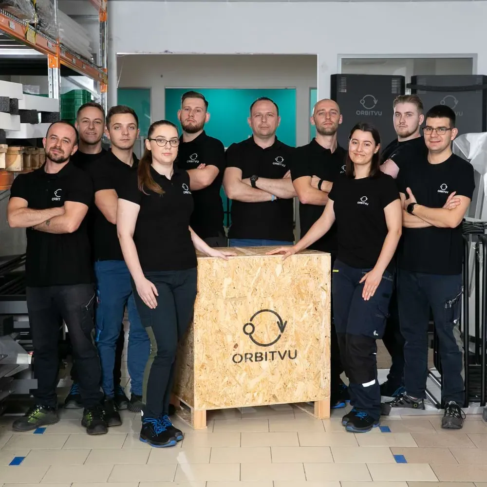 Orbitvus produktions- och logistikteam poserar med en trälåda med logotyp