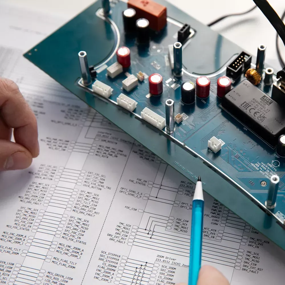 Ingenjör som granskar ett elektroniskt kretskort och ett kopplingsschema