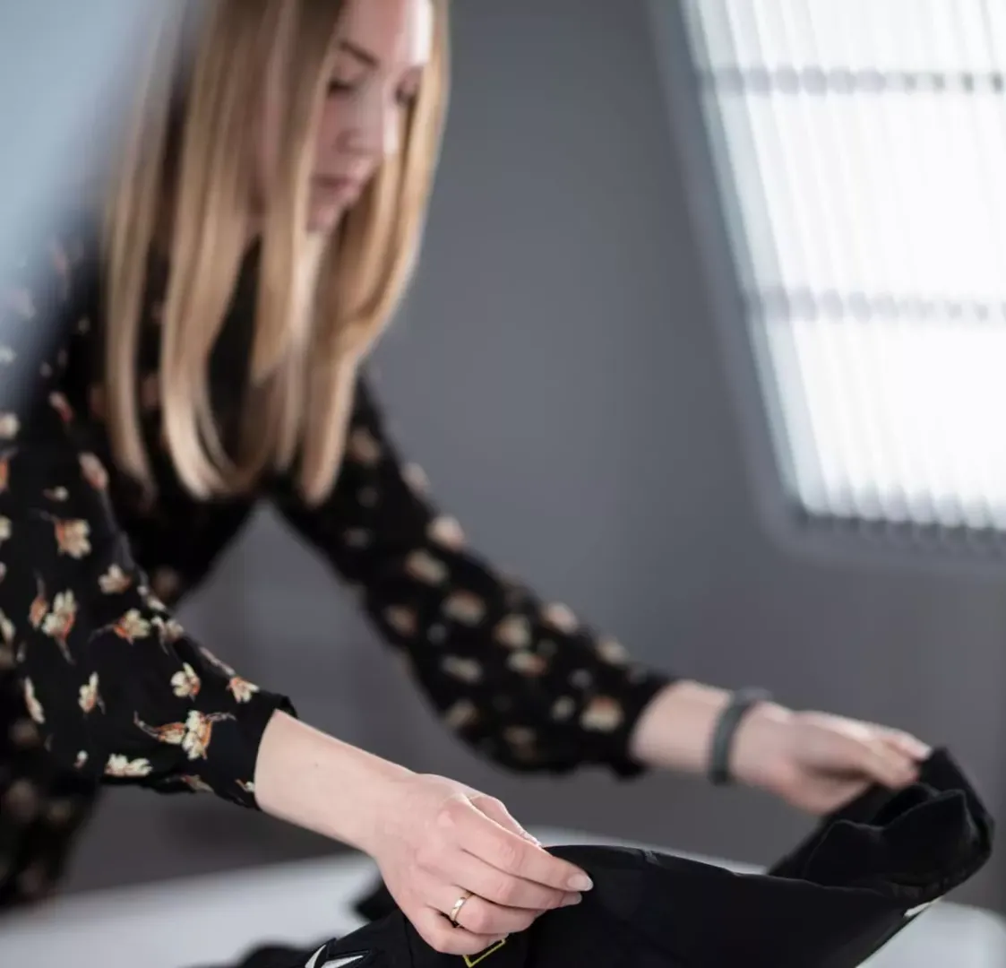 Produktstylist som arrangerar ett svart plagg för flat lay-fotografering
