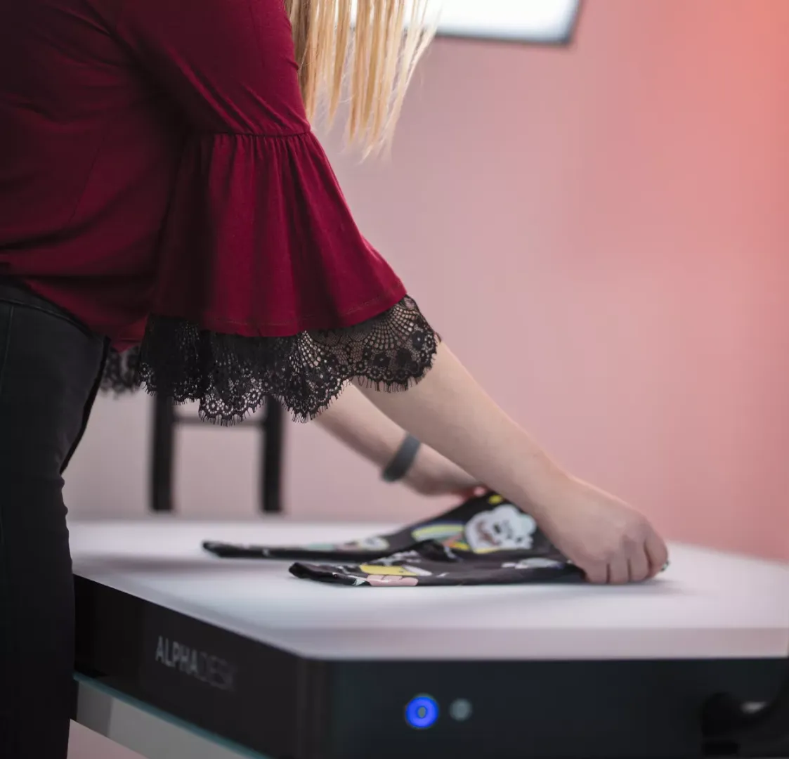 Kvinna som viker barnkläder på ett vitt skrivbord med Alphadesk